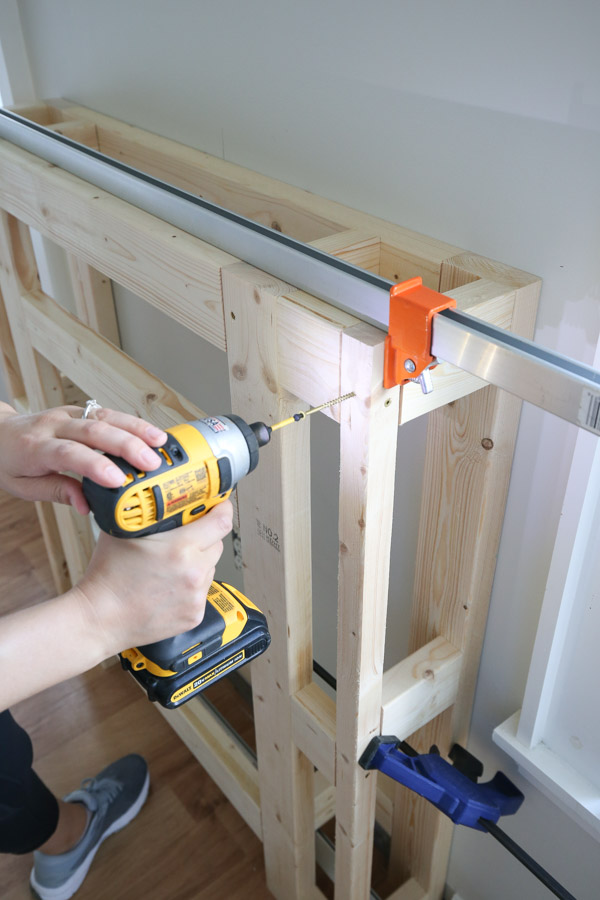 attaching front frame of DIY fireplace surround to back frame with clamps and screws