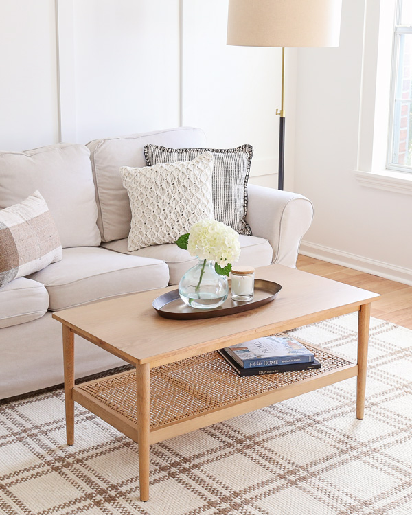 wood and cane coffee table with brass oval tray in living room