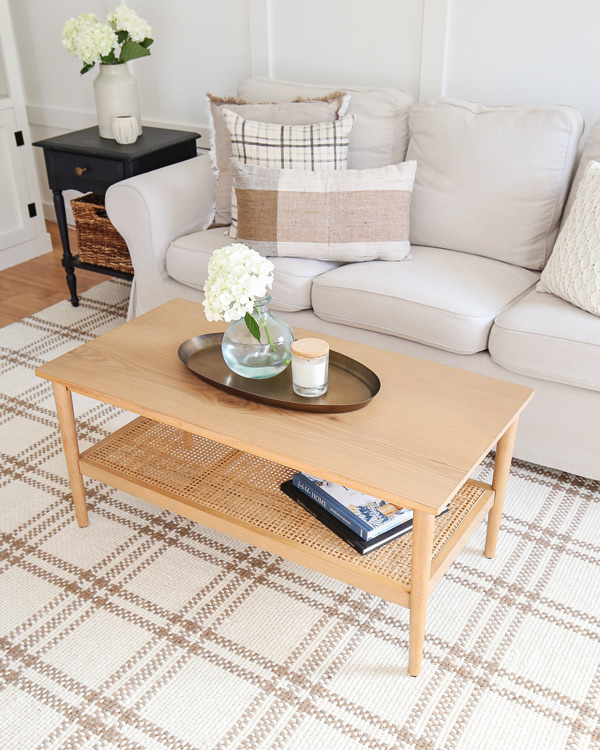 wood and cane coffee table with brass oval tray in living room