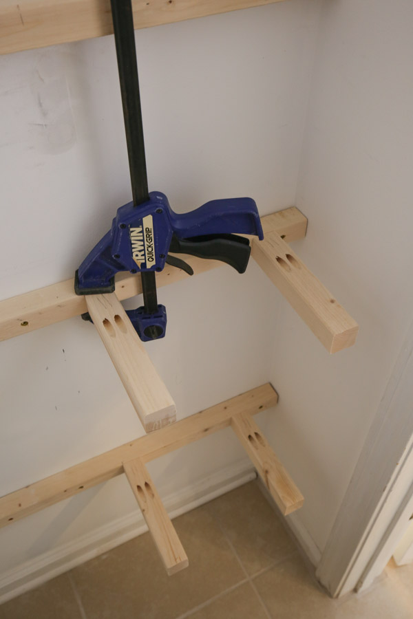 using clamp to attach 2x2 middle supports to pantry wall