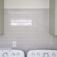 grey and white mosaic peel and stick tiles on laundry room backsplash