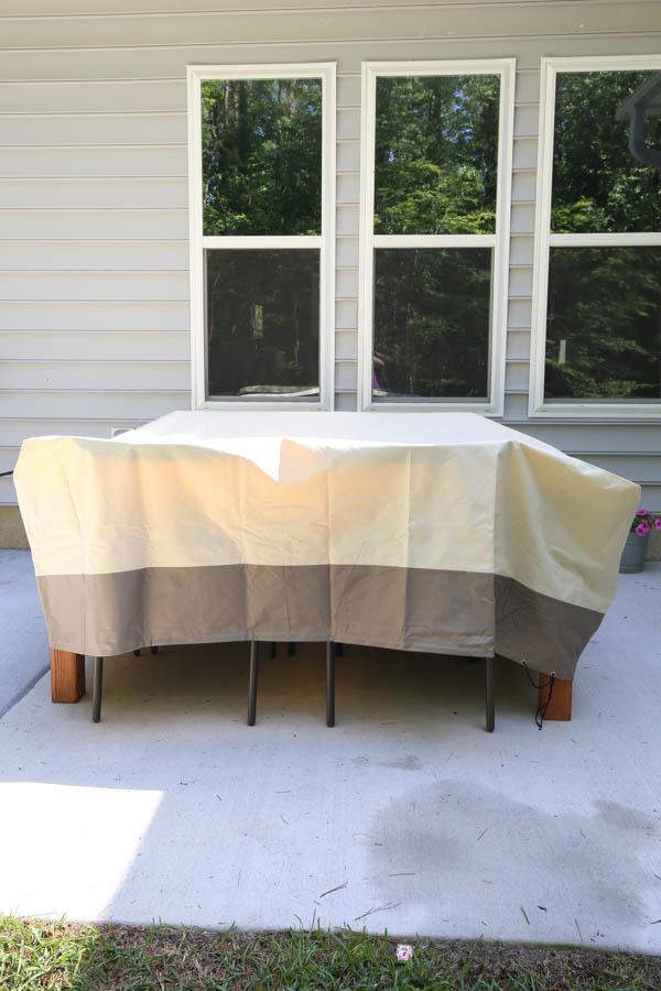 diy outdoor dining table and outdoor dining chairs covered with a patio furniture cover on uncovered patio