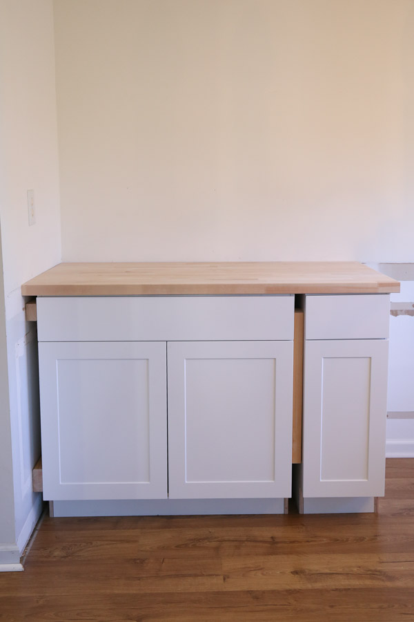 stock cabinets installed on corner wall with unfinished butcher block cut to size on top