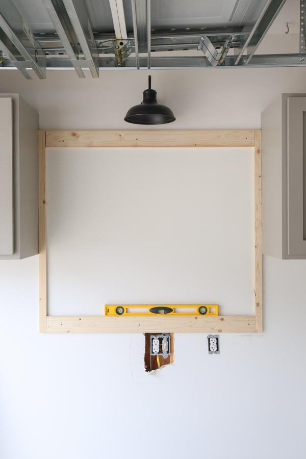 installing the pegboard back frame on the wall with level