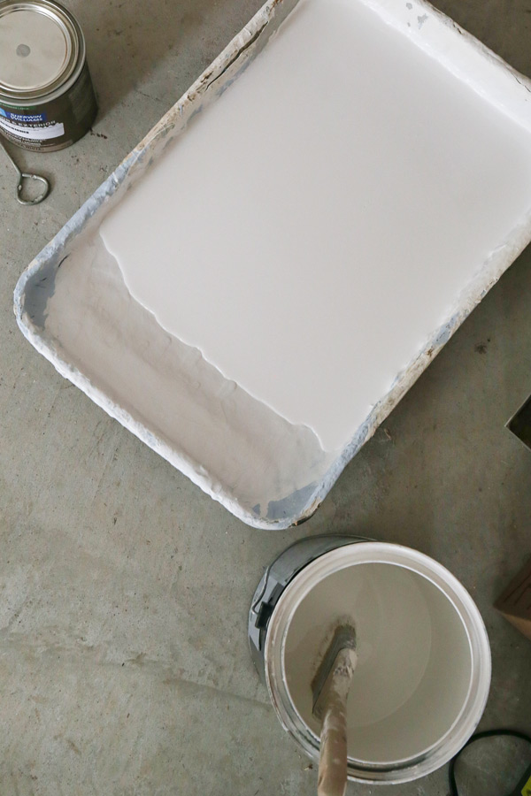 white paint in paint tray and can on garage floor