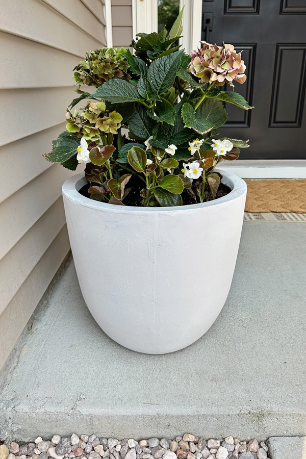 large outdoor planter that is lightweight concrete with flowers on front porch