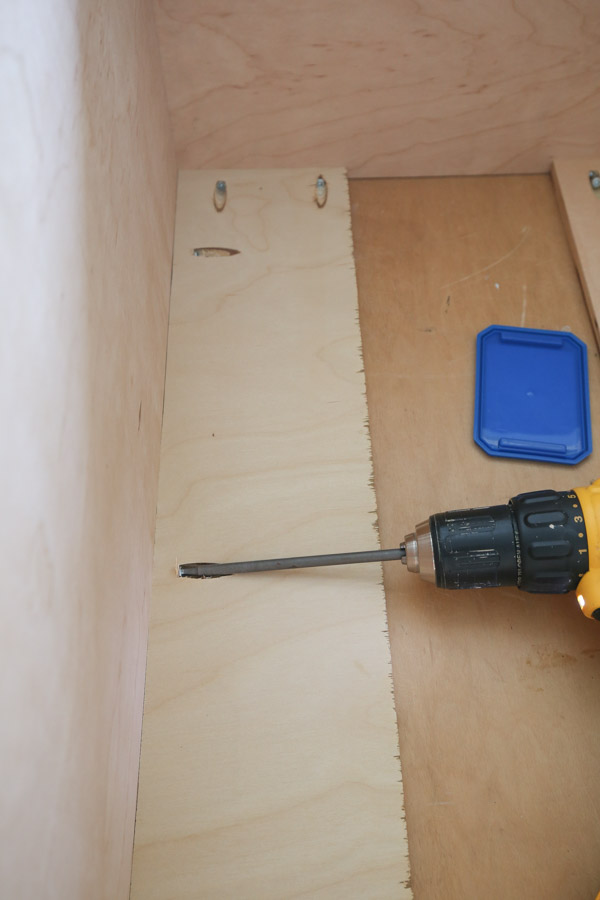 using drill to attach back support boards between cabinet side panels and to top panel