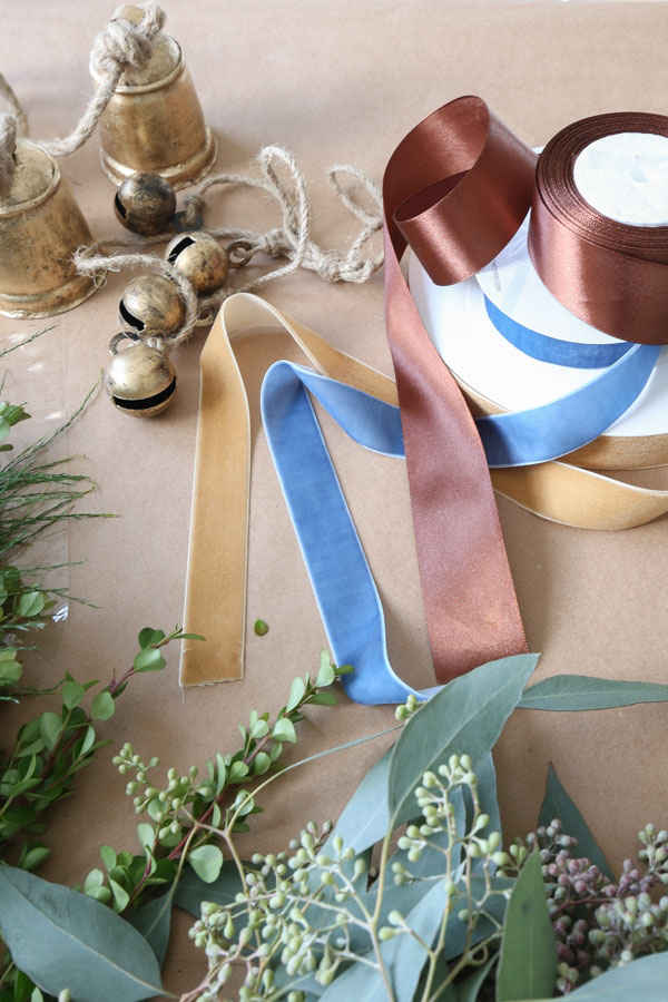 supplies for wreath: jingle bells, ribbon, and greenery