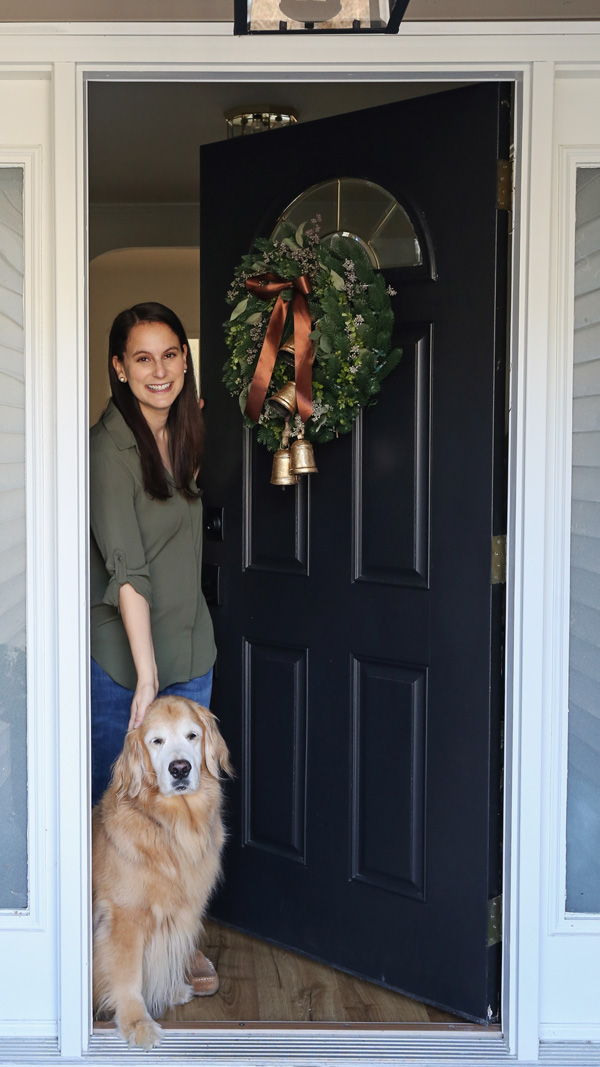 woman and dog opening door with DIY Christmas wreath on front porch