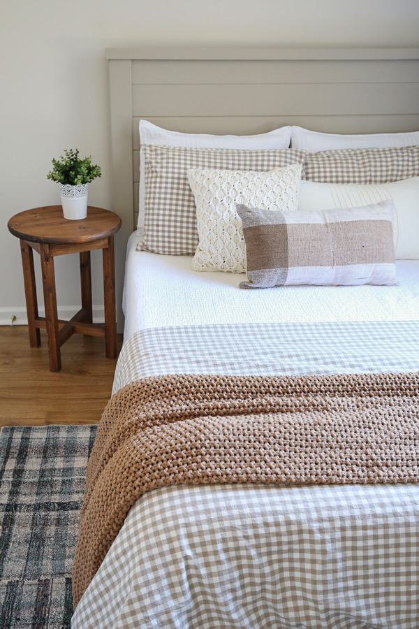 cozy layered bedding ideas with neutrals, cream, and brown colors and plaid rug