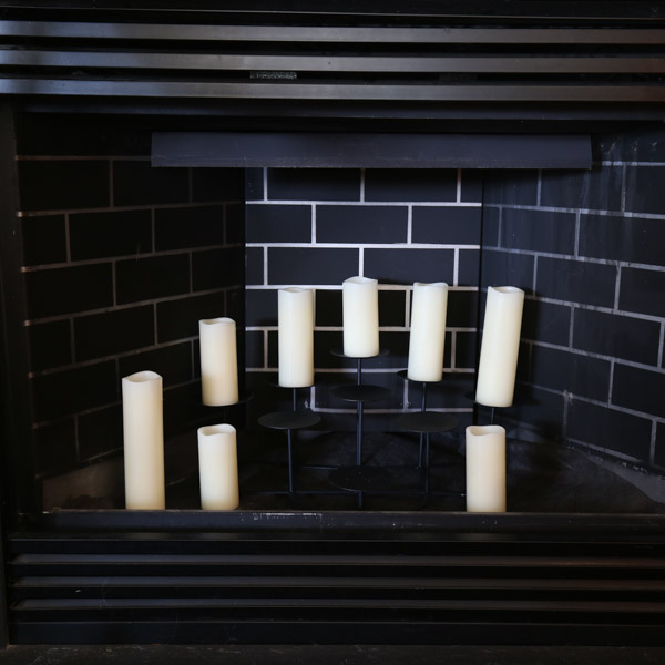 setting up the DIY christmas village in the fireplace with flameless candles and tiered candle stand before wood houses