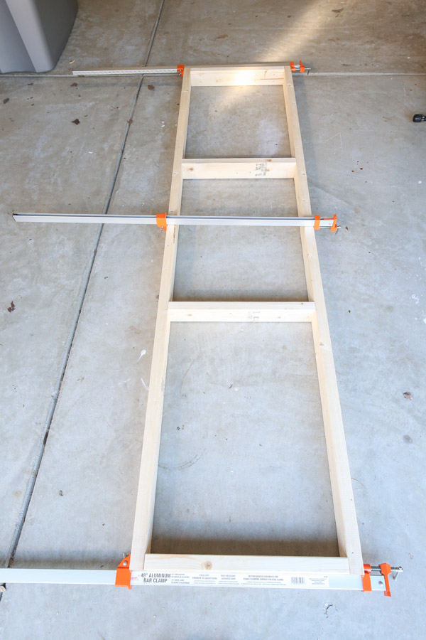 assembling shelf frame with clamps on garage floor
