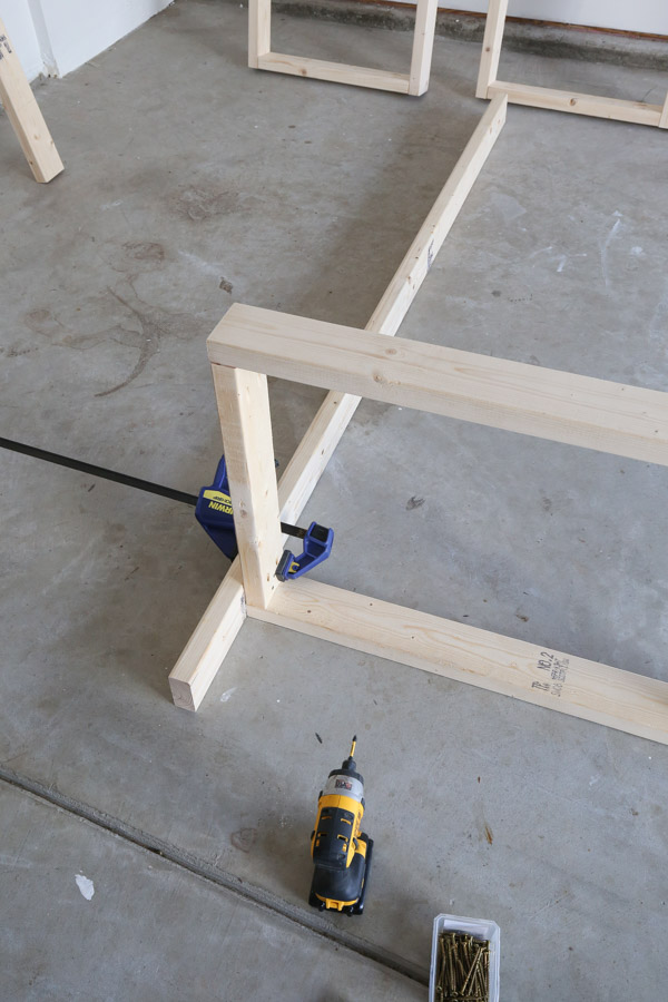attaching first shelf frame to vertical support with screws, wood glue, and clamp