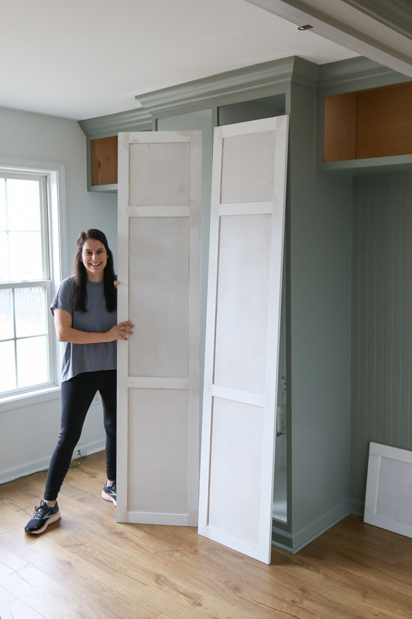 DIYer holding primed DIY cabinet doors for IKEA pax built in hack