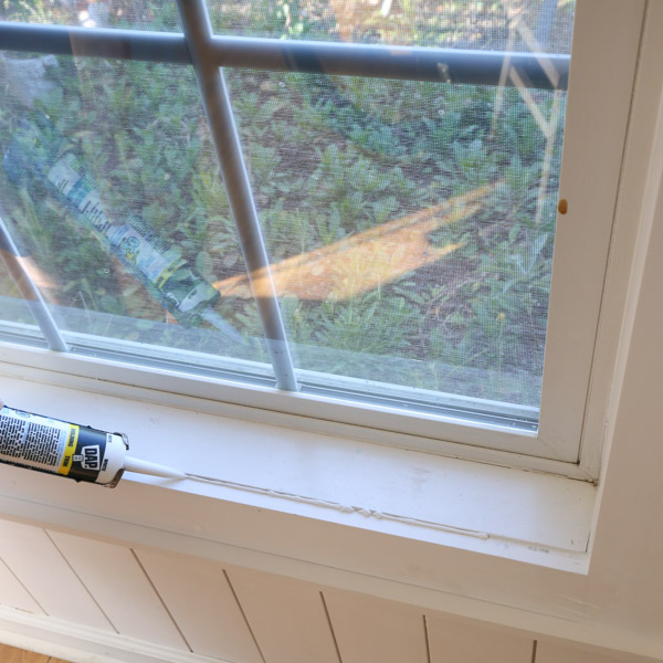 applying caulk to DIY window trim
