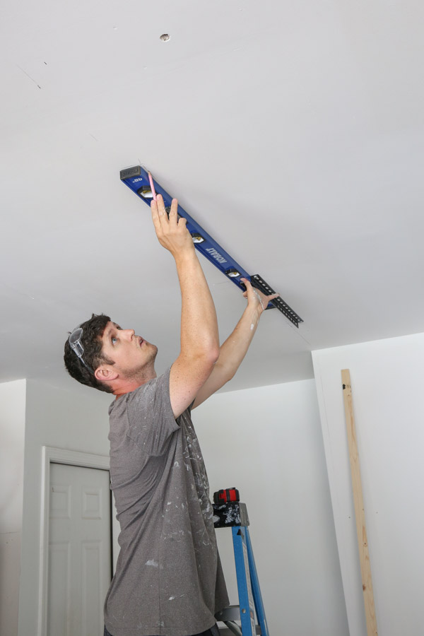 using a 4 ft level to help Install the ceiling brackets into the ceiling joists