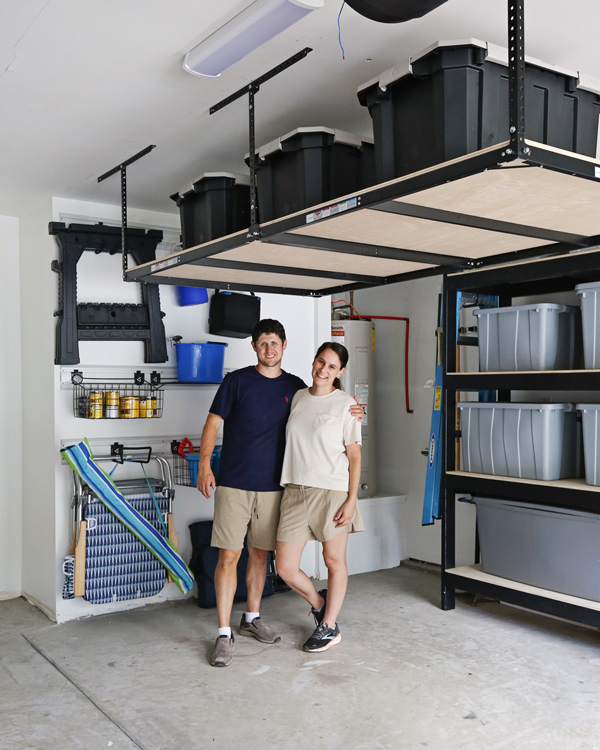 DIYers standing under DIY Garage Ceiling Storage shelves and next to wall storage