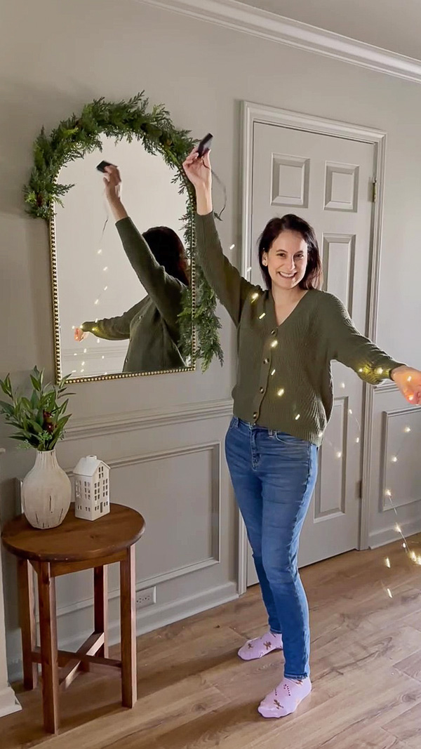Christmas decoration ideas for mirrors using garland and twinkle lights on entryway mirror