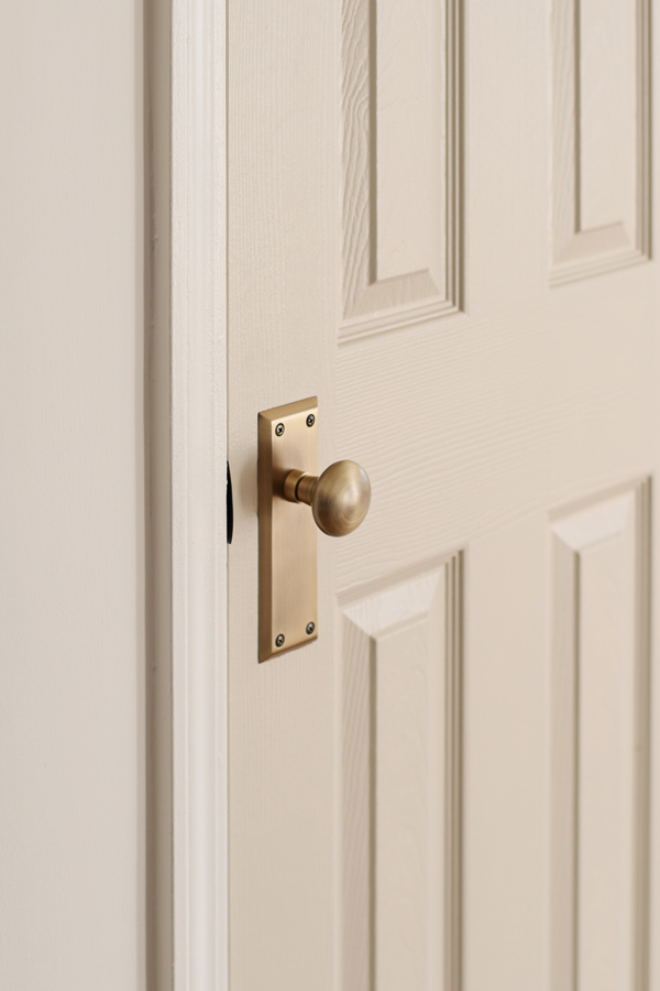 vintage antique brass door knob on gray door in kitchen