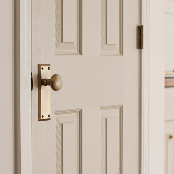 vintage antique brass door knob on gray door in kitchen