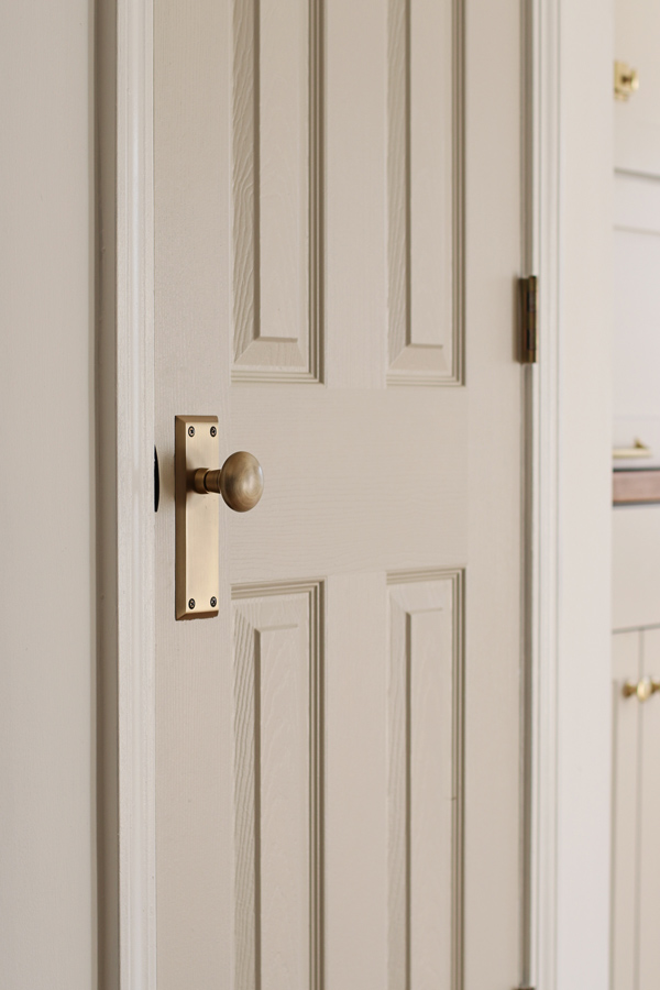 vintage antique brass door knob on gray door in kitchen