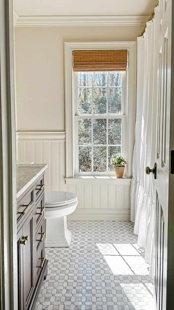 bathroom makeover with beadboard wainscoting, chair rail, marble floor tile, and bamboo shades on window