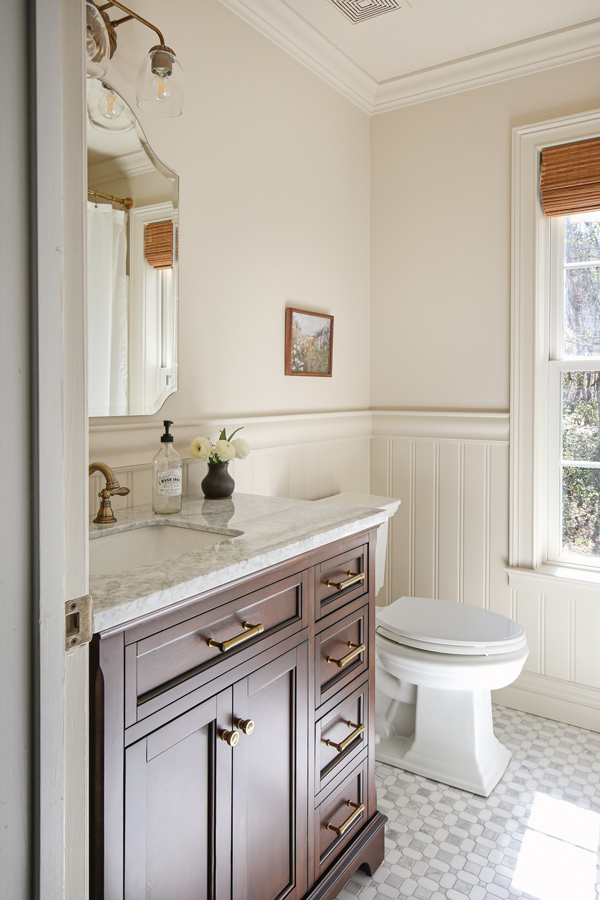 vintage charm bathroom makeover with frameless arch mirror, beadboard wainscoting, chair rail, marble floors and wood vanity