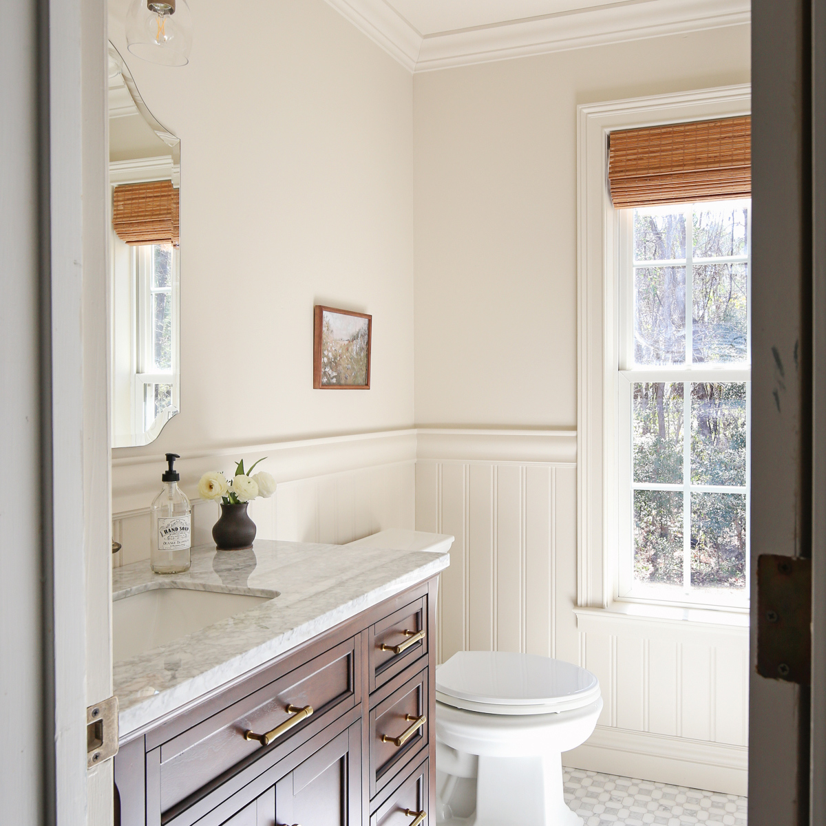 vintage charm bathroom makeover with frameless arch mirror, beadboard wainscoting, chair rail, marble floors and wood vanity
