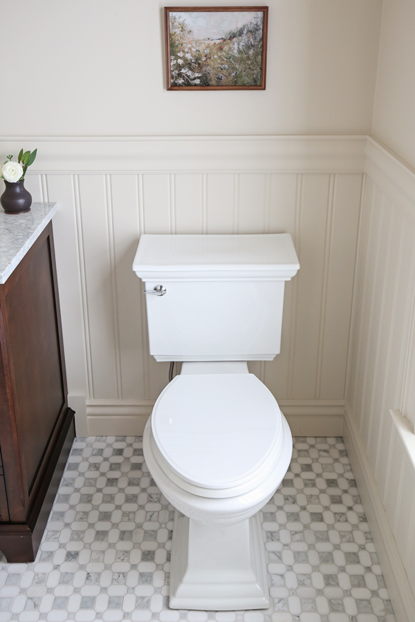 new Kohler toilet in bathroom makeover with beadboard, chair rail, and marble mosaic tile