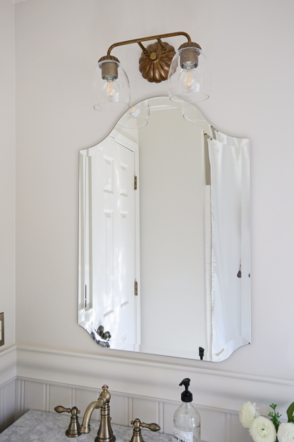 frameless arch shape mirror in bathroom with vintage look vanity light