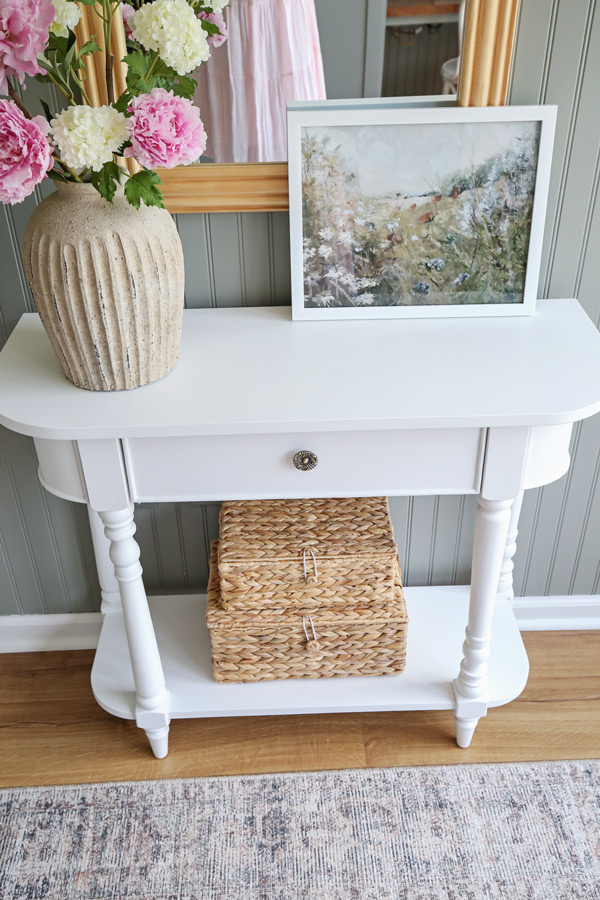 charming office wall decor ideas with vintage inspired console table, baskets, framed art, and handcrafted vase on beadboard wall painted green