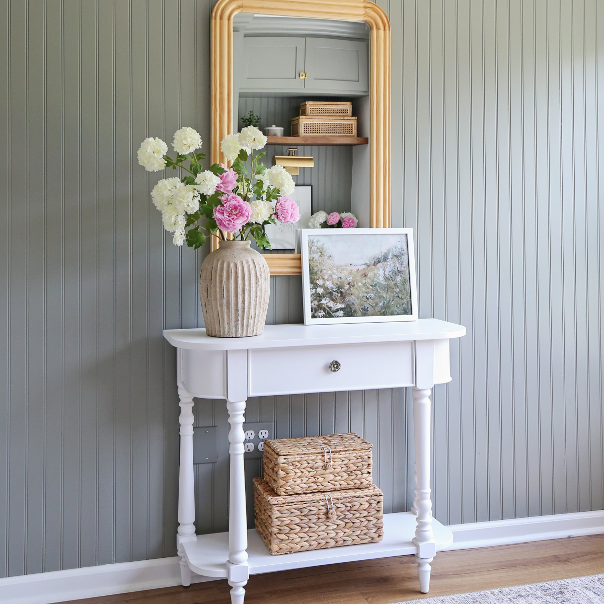 charming office wall decor ideas with vintage inspired console table, wood arch mirror, baskets, framed art, and handcrafted vase on beadboard wall