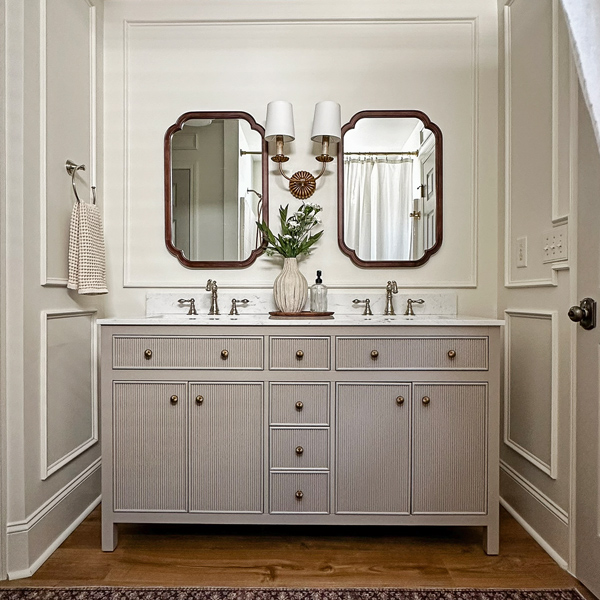 before and after budget bathroom makeover with double vanity, wood arch mirrors, and picture frame molding