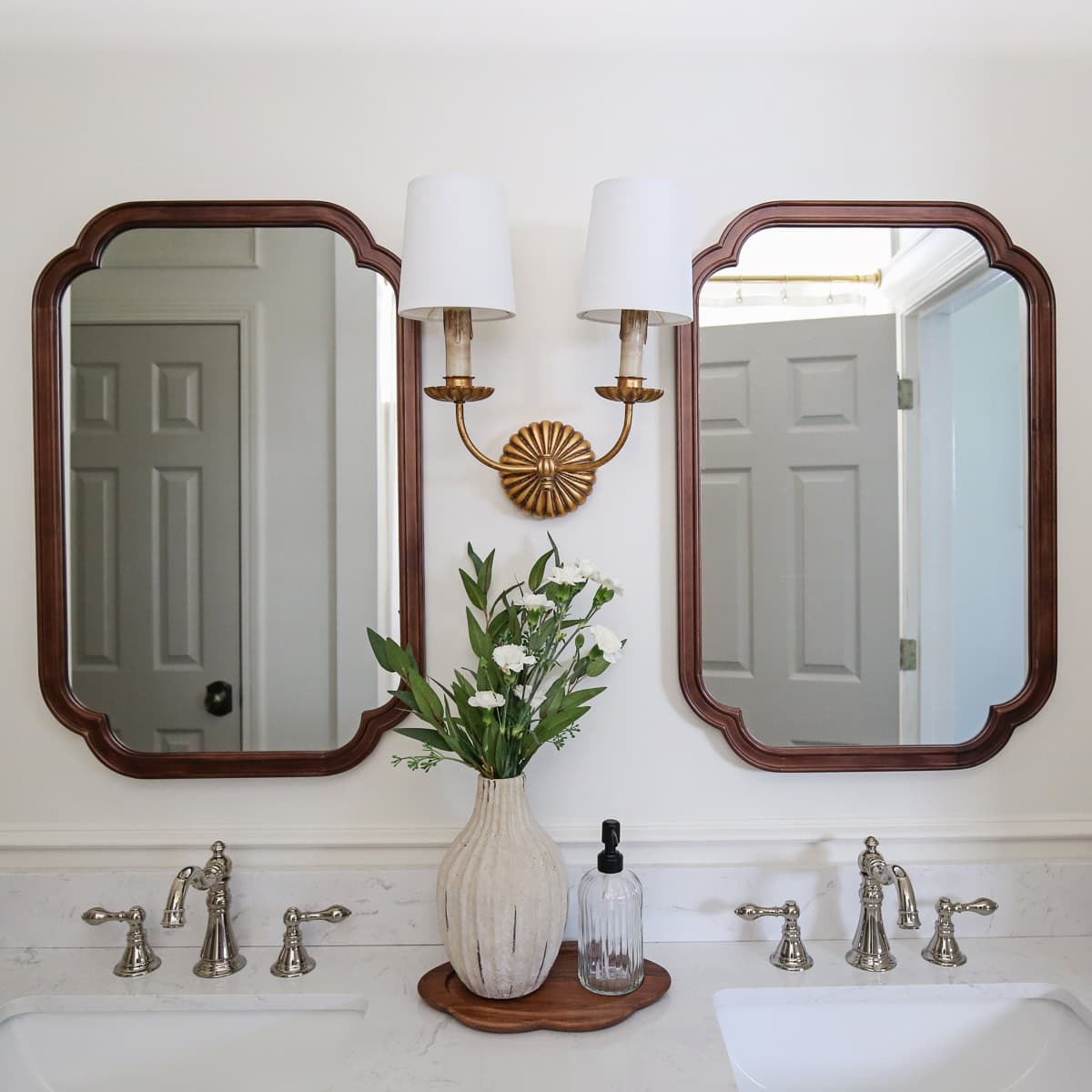 timeless, charming, classic, vintage look bathroom makeover with double wall sconce, and wood arch mirrors and polished nickel faucet