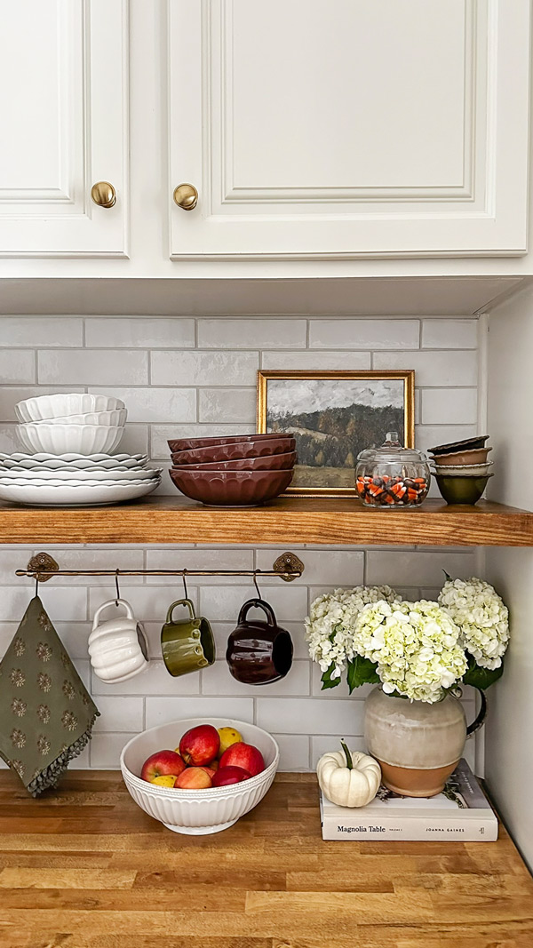 kitchen fall shelf decor and brown dishware and pumpkin mugs on kitchen rail