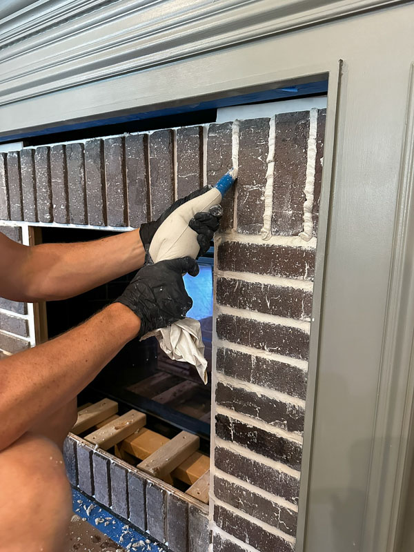 applying grout to the brick fireplace DIY