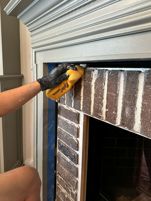 applying grout to the brick fireplace DIY