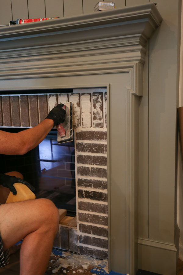 applying grout to the brick fireplace DIY