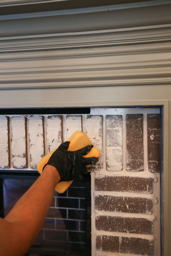 applying grout to the DIY brick fireplace