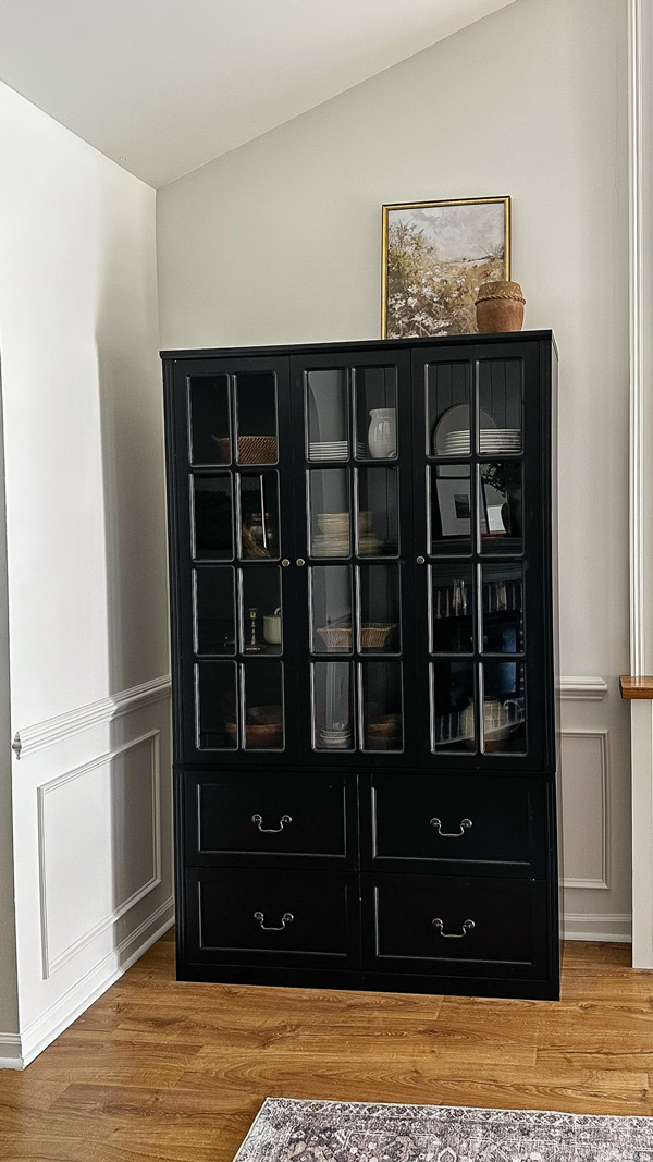 black storage cabinet with glass doors in corner nook with angled vaulted ceiling