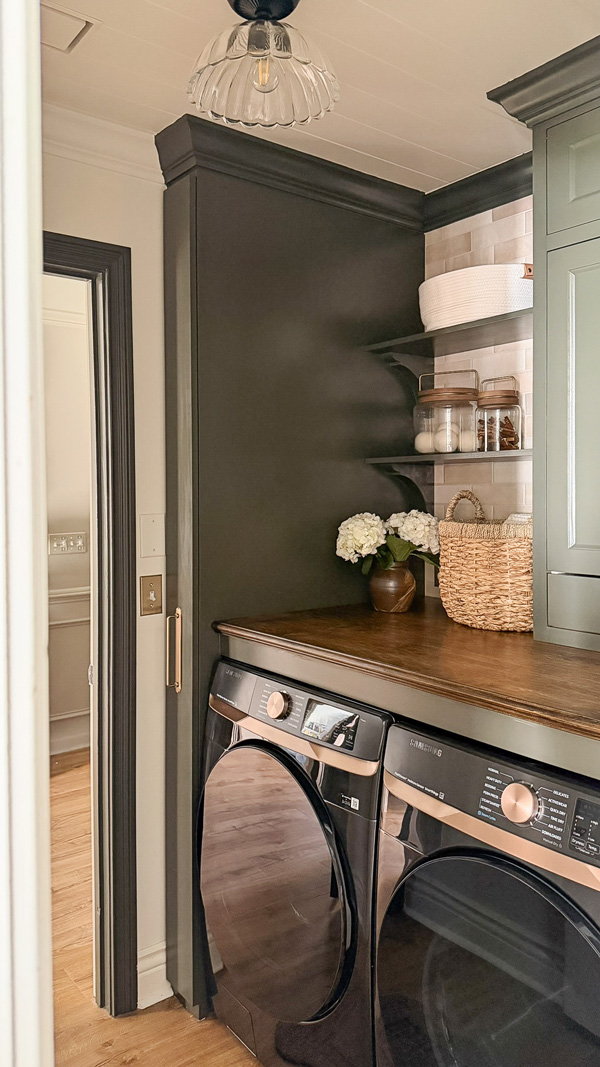 small laundry room makeover before and after with wood countertop over washer and dryer, wood shelves, and broom cabinet