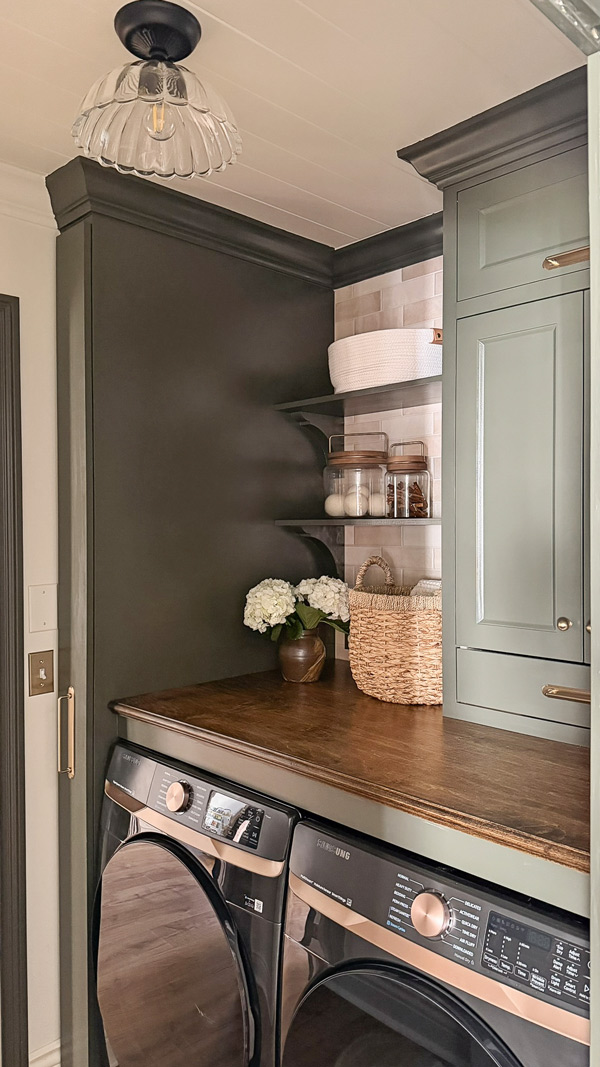 small laundry room makeover before and after with fatigue green Benjamin moore cabinets and with wood countertop over washer and dryer, wood shelves, and broom cabinet