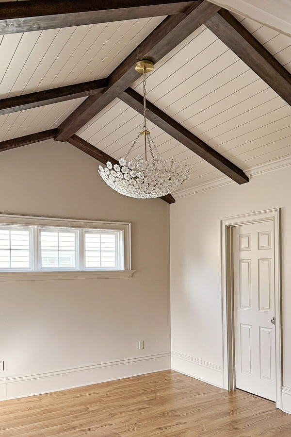dreamy chandelier in bedroom with vaulted ceilings and wood beams