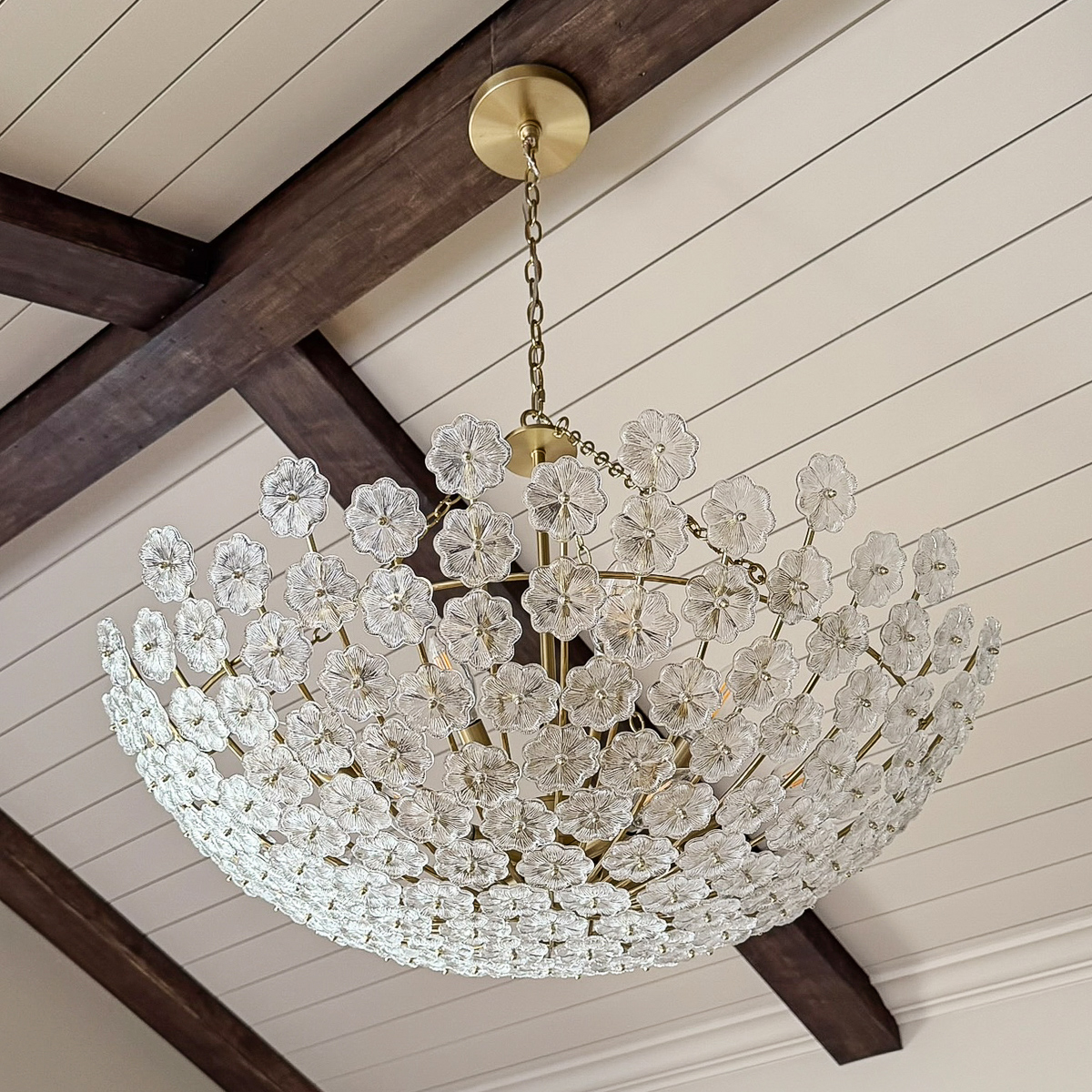 dreamy chandelier in bedroom with vaulted ceilings and wood beams